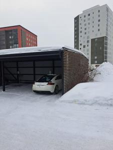 un coche blanco aparcado en un garaje con nieve en Luksuskolmio järvinäköalalla, en Jyväskylä