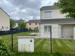 una cerca frente a una casa con un patio en Superbe Maison avec jardin, en Bezannes-les-Reims