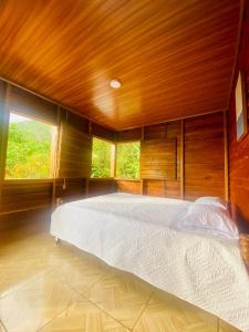 a large bed in a room with wooden walls at Cabaña Monarca in Turrialba