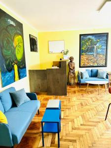 a living room with blue couches and paintings on the wall at HOSTEL ART & JOY in Pula