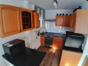 a small kitchen with wooden cabinets and a black counter top at Hibiskus - a83456 in Leutkirch im Allgäu