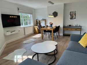 Luxury Apartment in Letchworth في ليتشوورث: غرفة معيشة مع أريكة زرقاء وطاولة