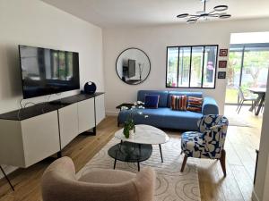 uma sala de estar com um sofá azul e uma televisão em Maison, 4 chambres, métro, climatisation em Villejuif