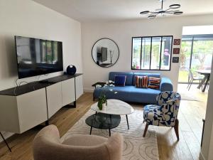 a living room with a blue couch and a tv at Maison, 4 chambres, métro, climatisation in Villejuif
