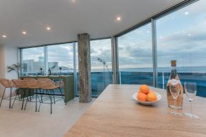 a table with a bottle of wine and a bowl of oranges at Gold Suite Canteras by Canarias Homelidays in Las Palmas de Gran Canaria