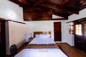 sypialnia z dużym łóżkiem i drewnianym sufitem w obiekcie Casablanca Ollantaytambo w mieście Ollantaytambo