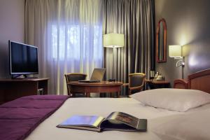 a hotel room with a bed, desk and television at Mercure Metz Centre in Metz