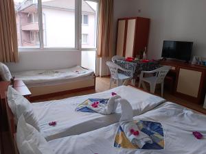 a small room with two beds and a table and a window at Стаи за гости Ники in Nesebar