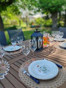 einen Holztisch mit Tellern und Weingläsern darauf in der Unterkunft Maison au calme avec jardin et local vélo in Jonquières