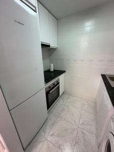 uma cozinha com armários brancos e um frigorífico em Alecus em Calpe