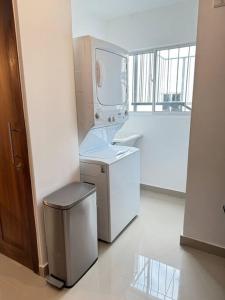 a laundry room with a washing machine and a trash can at Modern & Minimalist Apt with Pool,Gym & Security in Santiago de los Caballeros
