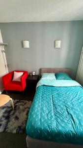 a bedroom with a bed and a red chair at Chambre Privée Kozy - Stade de France in Saint-Denis