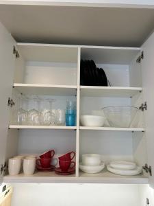 a white cabinet filled with dishes and bowls at Pine cone cozy apartment in Rīga