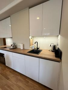 uma cozinha com armários brancos e um lavatório em Pine cone cozy apartment em Riga