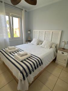 Un dormitorio con una gran cama blanca con toallas. en Oliva Nova flat in front of MET, en Oliva
