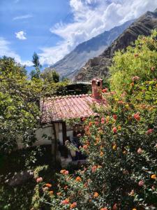 a house with flowers in front of a mountain at Casablanca Ollantaytambo in Ollantaytambo