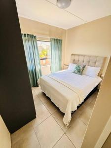 a bedroom with a large bed with a window at The Place at Mall of Africa 2 in Midrand