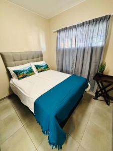 a bedroom with a bed with a blue blanket and a window at The Place at Mall of Africa 2 in Midrand +16 photos