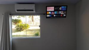 Pousada Chacara Princesa Isabel في ساو جوزيه دا بارا: غرفة مع نافذة مع تلفزيون على الحائط