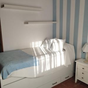een slaapkamer met een wit bed met gestreepte muren bij Casa Ayala in Ronda
