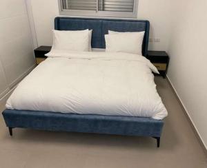 ein blaues Bett mit weißer Bettwäsche und Kissen darauf in der Unterkunft וילה הנסיכה ‏‏ in Mitzpe Ramon