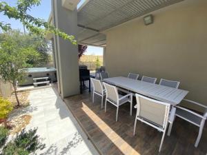 eine Terrasse mit einem Tisch, Stühlen und einem Grill in der Unterkunft וילה הנסיכה ‏‏ in Mitzpe Ramon