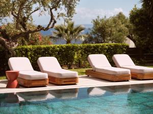 a group of lounge chairs next to a swimming pool at Cielo Luxury Villas in Zakynthos