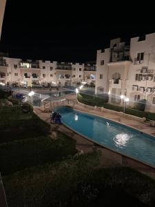 a swimming pool in front of some buildings at night at Lasirena mini egypt elsokhna in Ain Sokhna