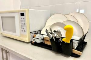 a basket of plates and utensils next to a microwave at Studio in the center with BBQ Patio and parking in Nahariyya