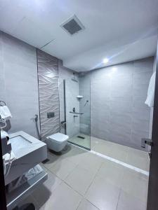 a bathroom with a shower and a toilet and a sink at شقق بيت المدينة للشقق المخدومة in Qabāʼ