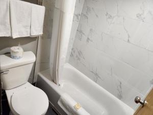 baño con aseo y bañera y papel higiénico en la parte superior en Twin Cities Inn, Mounds View, en Mounds View