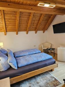 a bed with blue pillows in a room with wooden ceilings at Gästehaus Rana in Rust