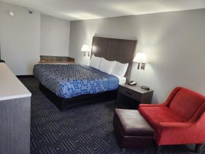 Habitación de hotel con cama y silla roja en Twin Cities Inn, Mounds View, en Mounds View