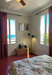 a bedroom with windows and a bed and a television at Plein coeur de Monaco, à 300 mètres à pied du port de Monaco, 4 pièces dans des escaliers vue mer exceptionnelle in Monte Carlo