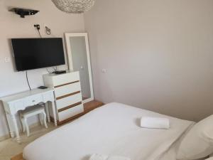 ein weißes Schlafzimmer mit einem Bett und einem TV in der Unterkunft צימר רמון in Mitzpe Ramon