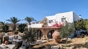 a white house with palm trees in front of it at Anoi House by the sea Agios Fokas Tinos in Tinos Town