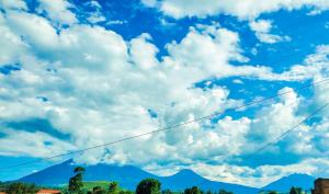 um céu azul com nuvens e uma montanha em Mianzi Guest House em Kisoro