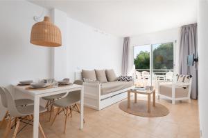 sala de estar blanca con mesa y sofá en Bauló Mar Apartments, en Can Picafort