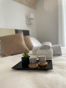 a tray with two cups and a plant on a bed at Dimora Santa Teresa in Monopoli