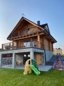 Złoty Groń log houses & apartments في ايستينبا: منزل أمامه ملعب