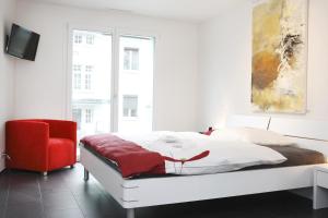 a bedroom with a bed and a red chair at Reloc Serviced Apart. Wallisellen in Wallisellen