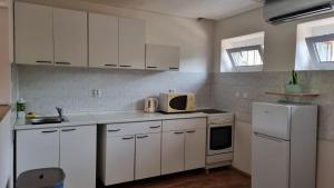 a kitchen with white cabinets and a white refrigerator at Apartmány Vinařství Klučov in Lstiboř