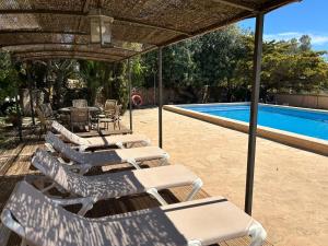 a group of lounge chairs and a swimming pool at Finca Albenyeta in Llucmajor