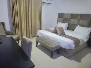 a bedroom with a large bed and a chair at Admiralty Hotel in Lekki