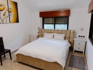 a bedroom with a large bed with white sheets at Apartment with patio and parking in Nahariyya