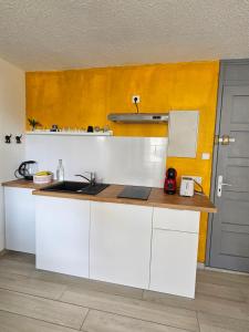 eine Küche mit weißen Schränken und einer gelben Wand in der Unterkunft Appartement idéalement placé face au lac in Soustons