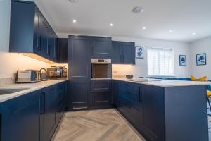 a kitchen with blue cabinets and white counter tops at North Horsham House in Horsham +3 photos
