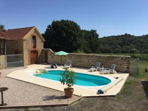 een zwembad met ligstoelen en een parasol bij Maison Lajus in Bassillon-Vauzé