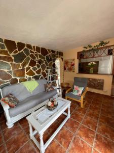 a living room with a couch and a stone wall at Casa Heydi in Breña Alta