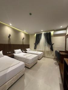 a hotel room with three beds and a desk at Sama Hotel Oraby in Cairo